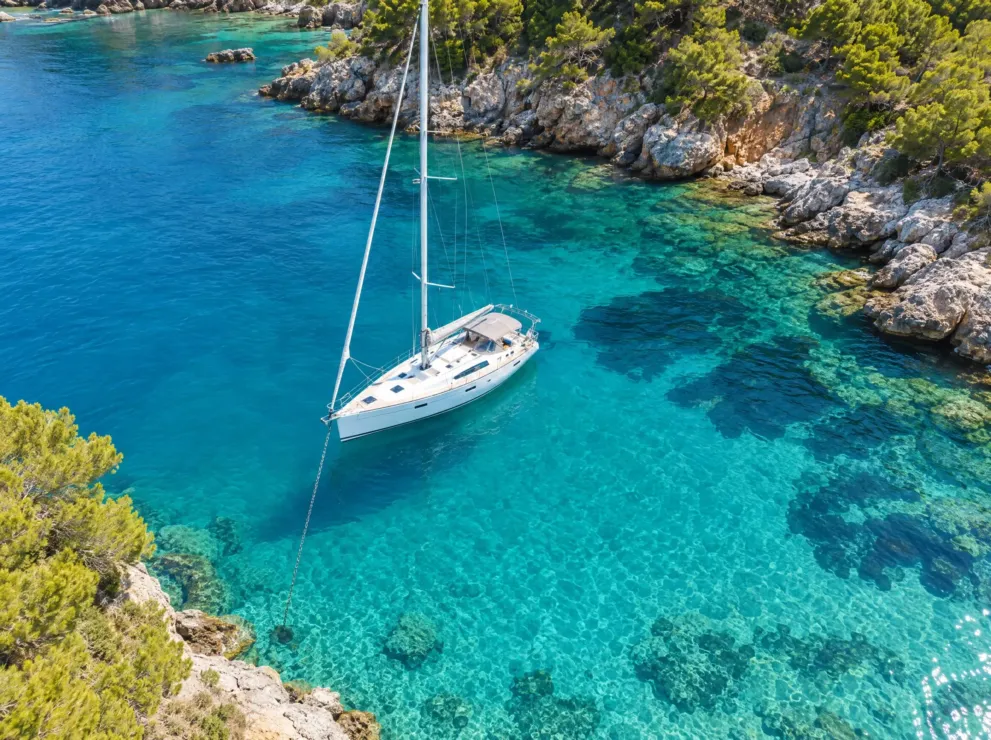 Segelyacht in einer türkisen Bucht von oben