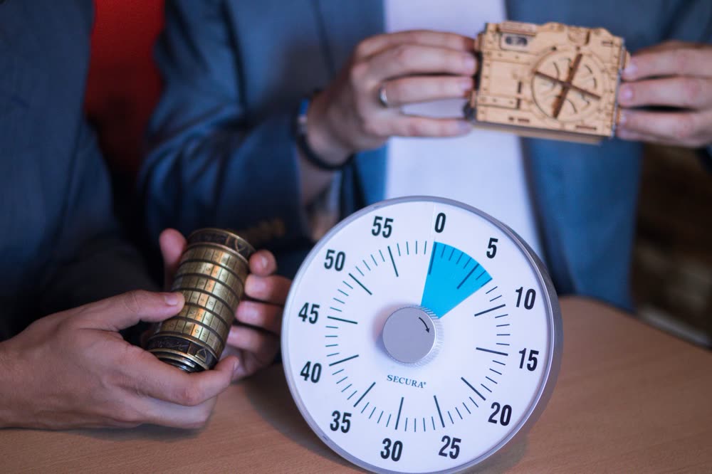 Hände mit Rätselschloss und Timer in einem Escape Room