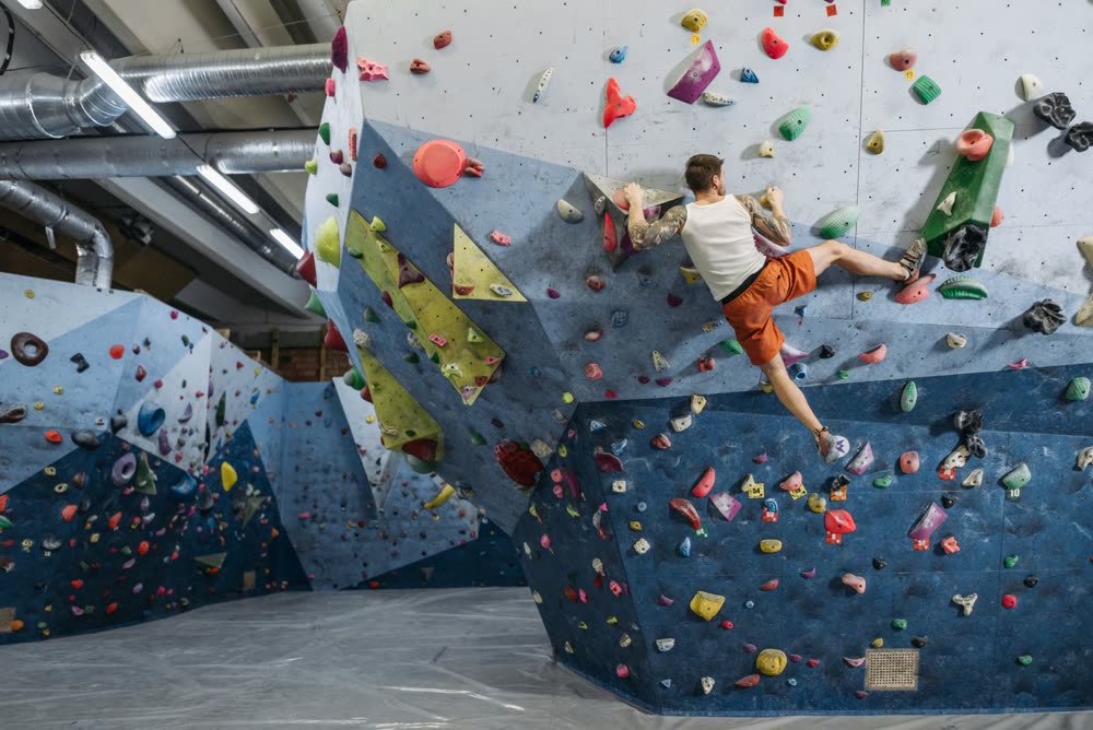 Kletterer an einer bunten Boulderwand in einer Halle
